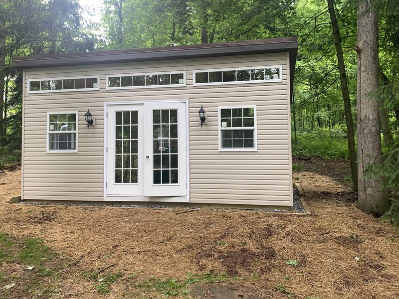 The office from outside, a small prefab building among the trees